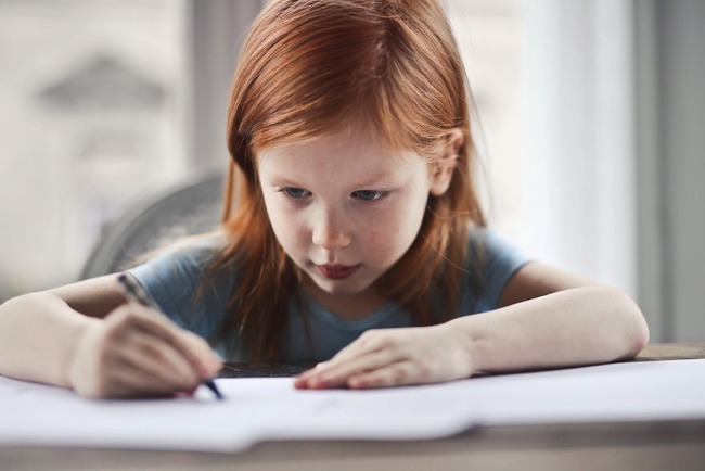Fetita de 7 ani care scrie intr-un caiet