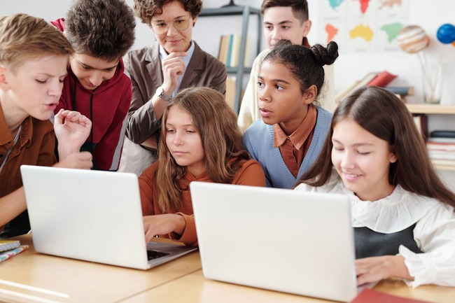Copii de gimnaziu studiind la laptop in sala de clasa