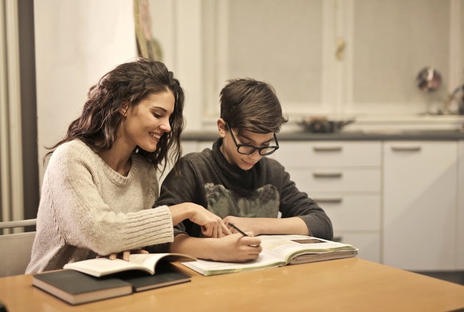 Adult care ajută la lecții un adolescent acasă
