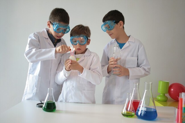 Băieți în halate albe făcând experimente științifice