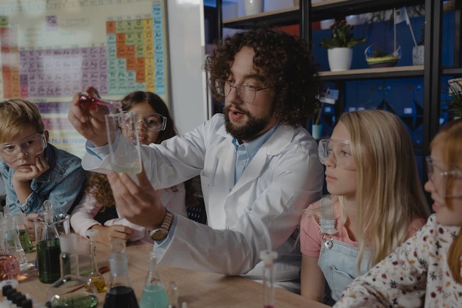 Copii și profesor care fac experimente științifice în laborator
