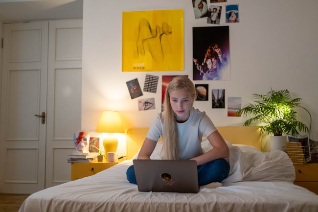 Adolescentă care se uită pe laptop în cameră