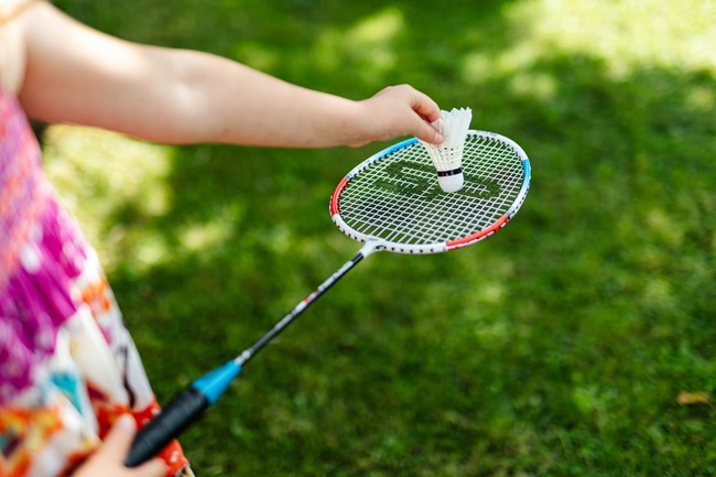 Fată care ține în mână o paletă de badminton