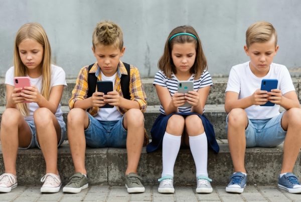 4 copii stand pe scari si uitandu-se pe telefon